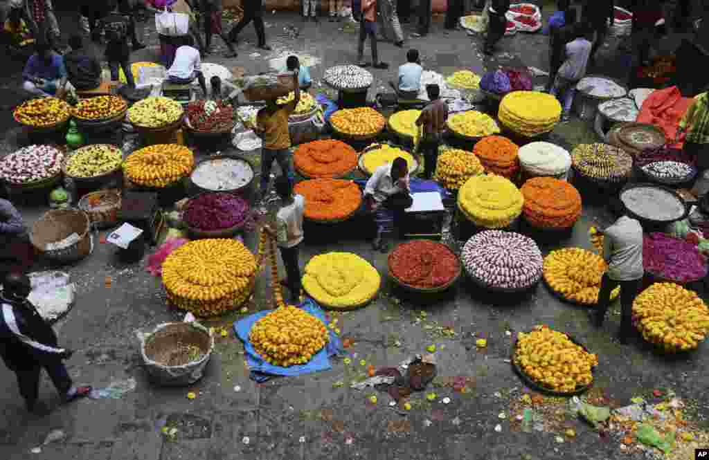 Indian vendors selling floral garlands wait for customers at a wholesale market in Bangalore, Aug. 9, 2018.