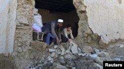 A man and his son clear the rubbles from their house after it was damaged by an earthquake in Behsud district of Nangarhar Province, Afghanistan, Oct. 27, 2015. 