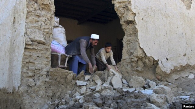 Un hombre y su hijo limpian su casa dañada por el terremoto del lunes, en el distrito Behsud de la provincia Nangarhar, en Afganistán.