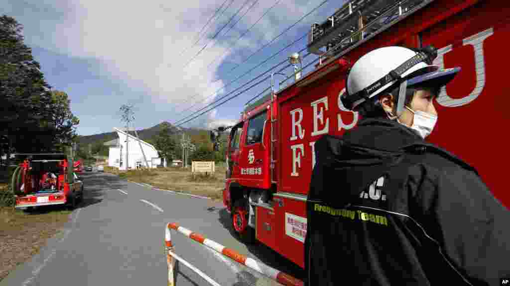 A firefighter allows a fire engine onto a restricted road leading to Mount Ontake as firefighters head to the mountain to aid in the rescue efforts of those stranded and injured, in Otaki Village, Nagano prefecture, Japan, Sept. 28, 2014.