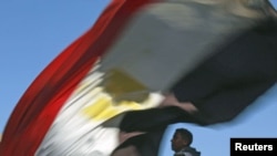 A man carries an Egyptian flag near Cairo's Tahrir Square where demonstrators are gathering to mark the first anniversary of Egypt's uprising, January 25, 2012.