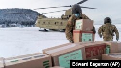 In this photo provided by the Alaska National Guard, soldiers from 1st Battalion, 207th Aviation Regiment, unload gifts from a CH-47 Chinook helicopter in Nanwalek, Alaska, during Operation Santa Claus, on Dec. 11, 2020.