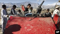 Afghans are seen around wreckage of a civilian car, which was hit by a roadside bomb in Laghman, east of Kabul, Afghanistan.