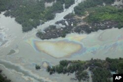FILE -Oil is seen on the creek water's surface near an illegal oil refinery in Ogoniland, outside Port Harcourt, in Nigeria's Delta region, March 24, 2011.