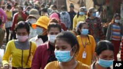 Garment factory workers wear face masks as they finish their work shift near Phnom Penh, Cambodia, Friday, Feb. 26, 2021. (AP Photo/Heng Sinith)