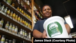 An assistant at the Fresh Earth store in Johannesburg, Kgomotso Mphshe, holds a product she sells regularly: natural, organic yoghurt produced by farmer Elizabeth Aymes and her workers.