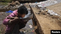 Một bé trai uống nước gần một dòng suối trong quận Fuyuan, tỉnh Vân Nam, Trung Quốc. Nhiều quốc gia ở Á Châu đang đối mặt với mối rủi ro xảy ra một vụ khủng hoảng nước nếu họ không giải quyết được sự quản lý yếu kém có thể dẫn tới tình trạng thiếu nước sạch nghiêm trọng.