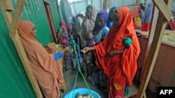 FILE - Newly displaced Somali women weigh their malnourished children as they try to receive medical treatment on the outskirts of Mogadishu, Somalia, on April 11, 2017. 