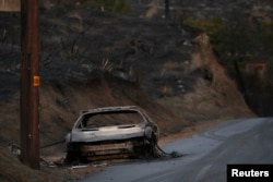 The burnt wreckage of a vehicle is seen along a road in the aftermath of the Woolsey fire in Malibu, Southern California, Nov.11, 2018.