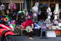 Seorang pedagang di pasar tradisional mengenakan masker sambil menunggu pelanggannya, saat pemerintah melonggarkan pembatasan darurat di tengah pandemi COVID-19 di Jakarta, 26 Juli 2021. (REUTERS/Willy Kurniawan)