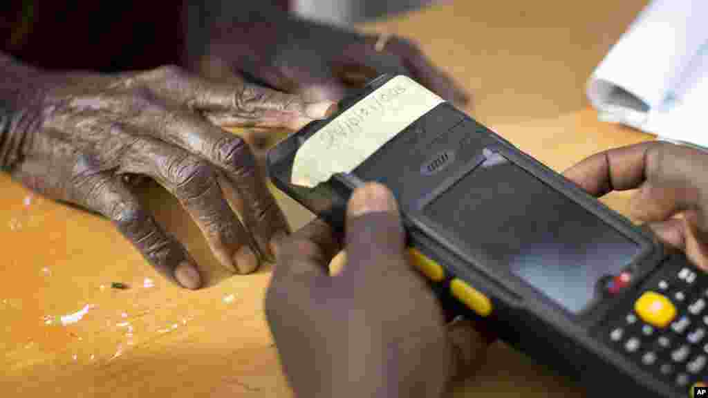 Une vieille femme nigériane fait valider sa carte de vote à travers un lecteur d&#39;empreintes digitales, avant de revenir voter plus tard dans la journée, dans la ville natale du candidat de l&#39;opposition le général Muhammadu Buhari, en Daura, Nigeria samedi 28 mars 2015.