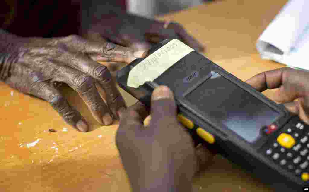 Seorang perempuan tua Nigeria tiba di TPS untuk melakukan validasi kartu pemilih menggunakan pemindai sidik jari, di Daura, Nigeria (28/3). (AP/Ben Curtis)