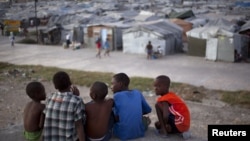 Sekelompok bocah laki-laki duduk di atas atap rumah yang hancur karena gempa Haiti 2010, di seberang sebuah kamp yang mereka tinggali di Port-au-Prince, Januari 2013. (Foto: Dok)