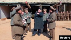 ທ່ານ Kim Jong Un (ກາງ) ຜູ້ນໍາເກົາຫລີເໜືອ ຢ້ຽມຢາມ ໜ່ວຍຍິງປືນໃຫຍ່ໄລຍະໄກ ຂອງກອງທັບປະຊາຊົນ ເກົາຫລີເໜືອ ເລກທີ 641 ໃນວັນທີ 11 ມີນາ 2013