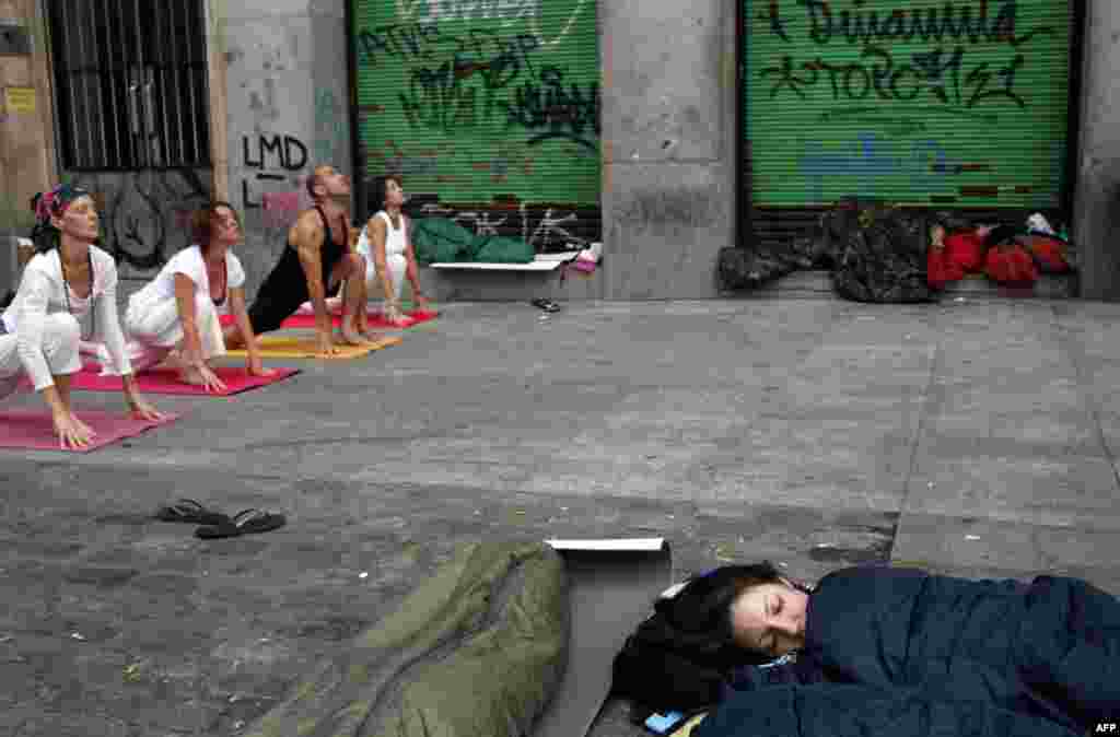 May 26: Demonstrators sleep as people practice yoga at Madrid's Puerta del Sol. Tens of thousands of protesters have joined those camped out for the past twelve days to protest against the government's handling of the economic crisis which broke out in 20