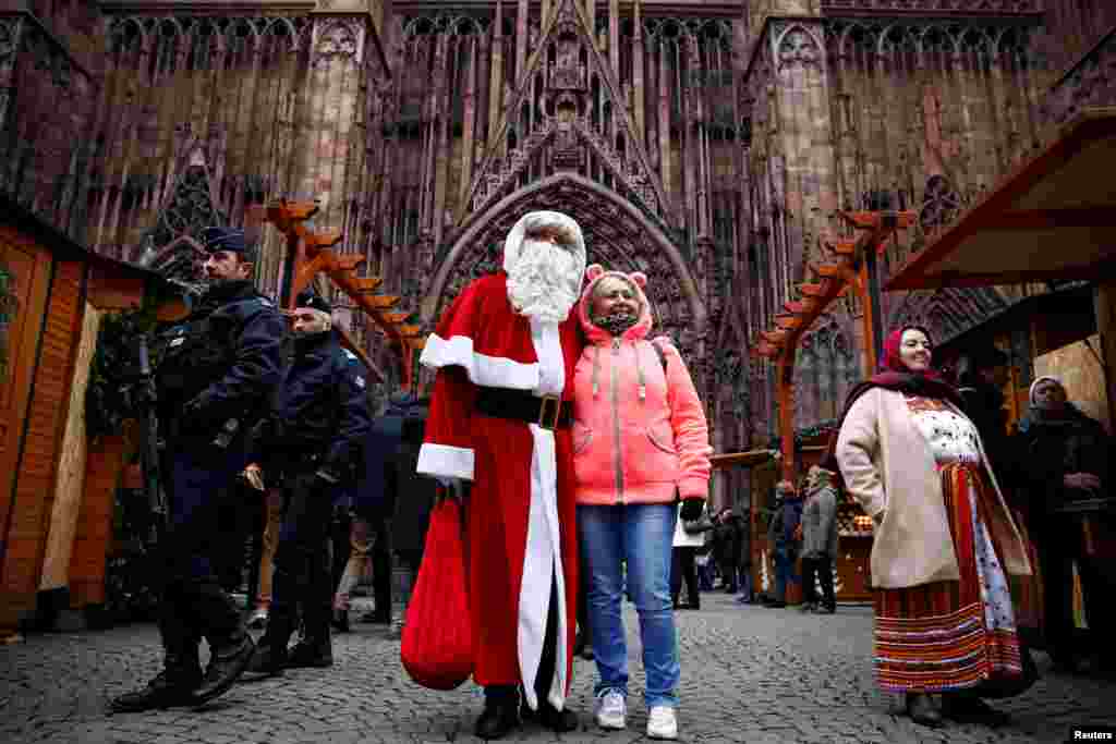 French police patrol outside the Strasbourg Cathedral as a man dressed as Father Christmas poses with a tourist, in Strasbourg.