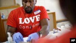 FILE - Reggie Batiste (l) program manager with AIDS Healthcare Foundation, administers a free HIV test as part of National HIV Testing Day, June 27, 2013, in Atlanta.