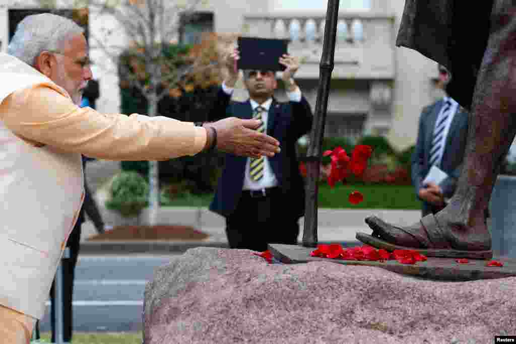 India's Prime Minister Narendra Modi scatters flower petals at the feet of the Mahatma Gandhi Statue outside the Indian Embassy in Washington, Sept. 30, 2014. 