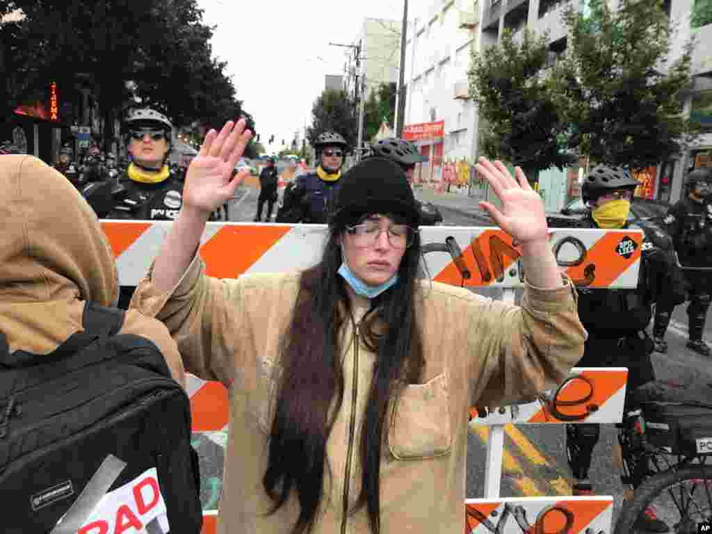 A protester stands with her hand up in front of a road blocked by Seattle police in the Capitol Hill Organized Protest zone, Washington.&nbsp;Police in Seattle have torn down demonstrators&#39; tents in the city&#39;s so-called occupied protest zone after the mayor ordered to clear it.