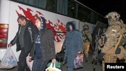 Members of pro-Russian rebels walk past Ukrainian servicemen during an of exchange of prisoners of war outside Donetsk, Ukraine, Dec. 26, 2014.