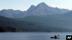 FILE - A woman kayaks on Kintla Lake in Glacier National Park, Mont. A grizzly bear attacked and killed a 38-year-old mountain biker Wednesday, June 29, 2016.