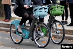 Riders present the new Velib' Metropole self-service public bicycles by the Smovengo consortium during a media presentation in Paris, France, Oct. 25, 2017.