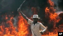 A supporter of the Orange Democratic Party hold up a machete in front of a burning baricade during riots in the Kibera slum in Nairobi, (File photo).