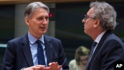Britain's Chancellor of the Exchequer Philip Hammond, left, talks with Luxembourg's Finance Minister Pierre Gramegna during a round table meeting of EU finance ministers at the EU Council building in Brussels on Jan. 27, 2017.