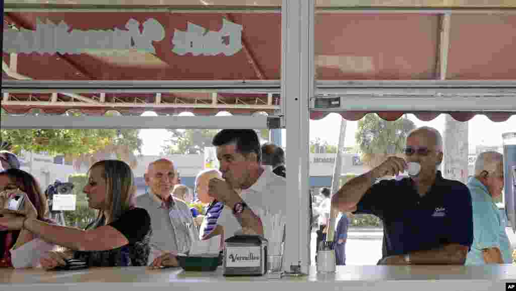 Warga Kuba Amerika Jose Feliu (kanan) menikmati kopi Kuba saat bersiap untuk bekerja di daerah Little Havana di Miami, Florida (18/12). (AP/Alan Diaz)