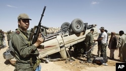 A Tunisian army soldier stands guard near an overturned car which belongs to forces loyal to Libyan leader Moammar Gadhafi after clashes with Tunisians and rebel fighters in Dehiba near the Libyan and Tunisian border crossing of Dehiba, April 29, 2011
