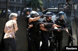 A woman reacts as Argentine policemen fire rubber bullets during clashes outside the Congress in Buenos Aires, Argentina, Dec. 14, 2017.