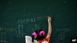 A girl writes on a chalkboard during a math class at Dongba Experimental School, a school for the children of migrant workers, in Beijing, August 25, 2011.