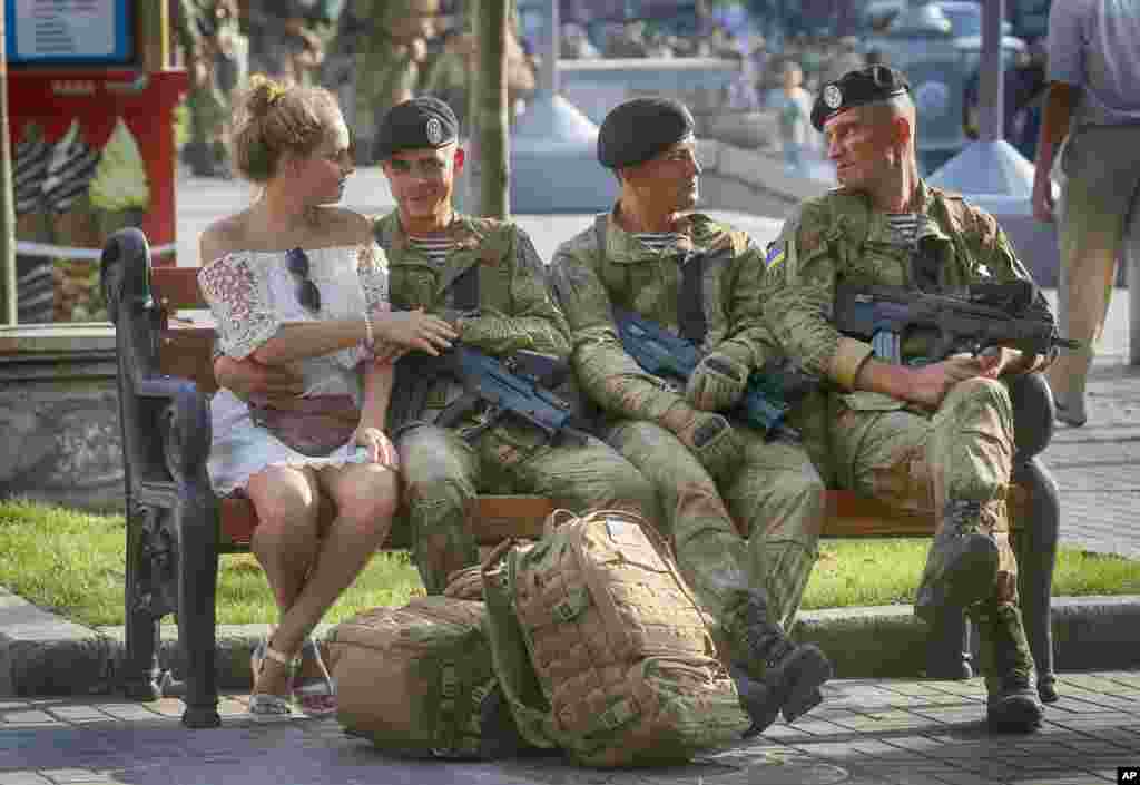 A soldier shares a tender moment with his girlfriend while other soldiers rest during a rehearsal of a military parade a few days before the Independence Day in Kyiv, Ukraine.
