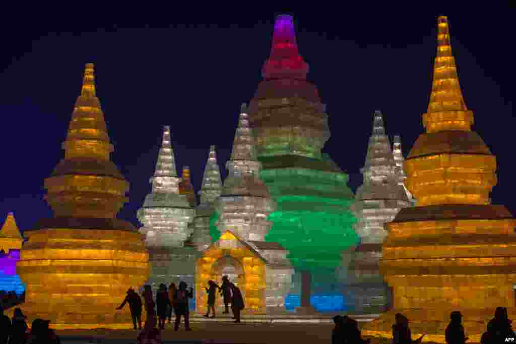 People visit ice sculptures illuminated by colored lights at the Harbin Ice and Snow Festival to celebrate the new year in Harbin, China.