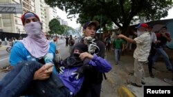 Petugas tengah menolang seorang pemrotes yang terluka saat terjadi bentrokan dengan polisi anti huru-hara, pada aksi unjuk rasa menentang Presiden Venezuela Nicolas Maduro di Caracas, Venezuela, 201 April 2017. (REUTERS/Marco Bello).