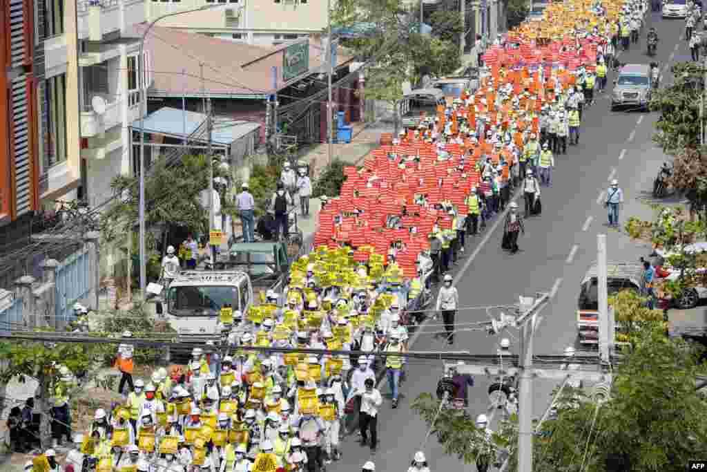 Protesters hold signs as they march on a road during a demonstration against the military coup in Mandalay, Myanmar.