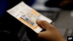 在德州奥斯汀的一处早期投票站，一名选举官员检查一位选民的照片身份证（2014年2月26日）
