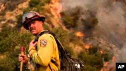 A crew member with California Department of Forestry and Fire Protection (Cal Fire) battles a brushfire on the hillside in Burbank, Calif., Saturday, Sept. 2, 2017. 