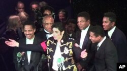 Michael Jackson (tengah), bersama pendiri Motown Records Berry Gordy (kedua dari kiri) dan saudara laki-laki Michael (dari kiri), Marlon, Tito, Jackie (depan) dan Jermaine. The Jackson 5 menerima penghormatan masuk ke jajaran ‘Rock and Roll Hall of Fame,’ 6 Mei 1997, di Cleveland. (Foto: AP/dok)
