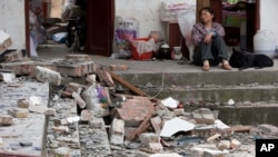 2013年4月21日四川省芦山县古城村的一名妇女望着她的被地震摧毁的房屋。