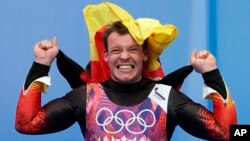 Felix Loch of Germany jumps onto the podium after he won the gold medal during the men's singles luge final at the 2014 Winter Olympics, Feb. 9, 2014, in Krasnaya Polyana, Russia. 