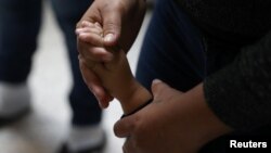 A woman holds a child's hand as undocumented immigrant families are released from detention at a bus depot in McAllen, Texas, June 22, 2018.