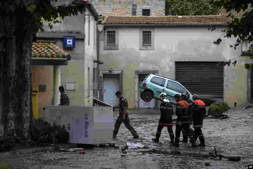 Rescue workers and soldiers walk in the town of Villegailhenc, southern France, after flash floods.