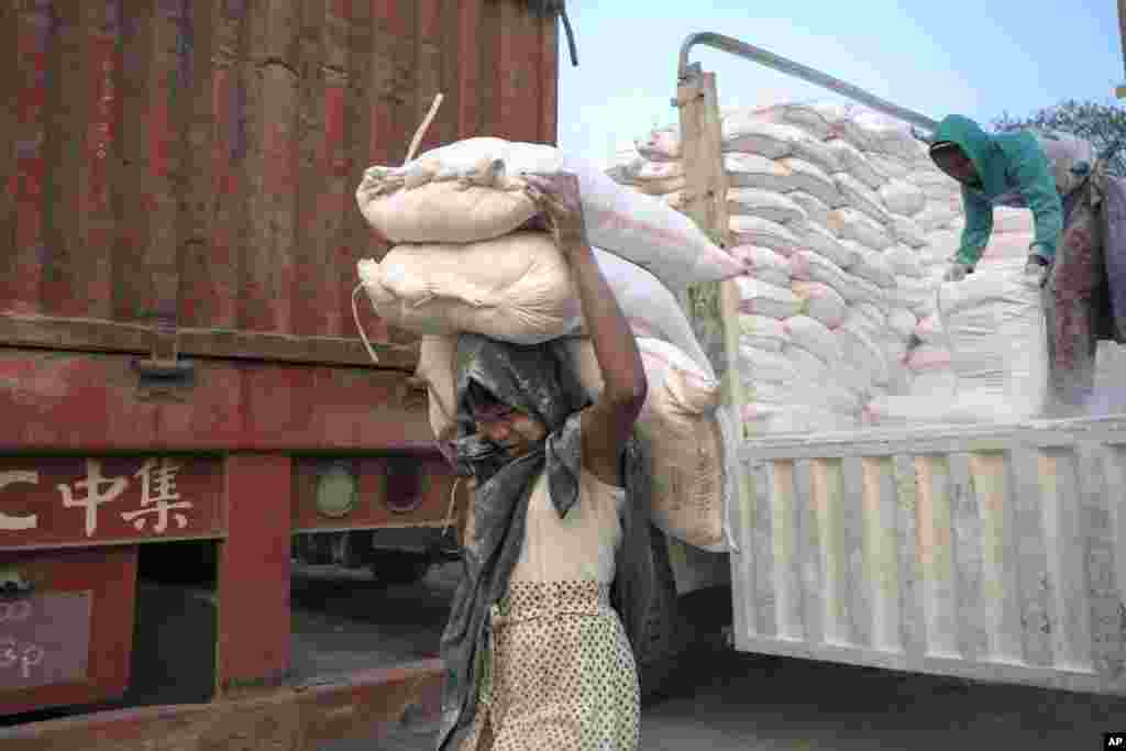 A 14-year-old Myanmar girl carries three bags of powdered limestone to load onto a boat on the bank of Ayeyarwaddy River, on International Women’s Day in Mandalay, Myanmar, March 8, 2016. 