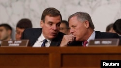 Senate Intelligence Committee ranking member Mark Warner (D-VA) (L) talks with Chairman Richard Burr (R-NC) during former FBI Director James Comey's appearance before a Senate Intelligence Committee hearing on Russia's alleged interference in the 2016 U.S electrion, June 8, 2018.
