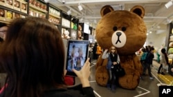 Turis berfoto dengan karakter beruang Line di toko cenderamata Line Friends di Seoul. (AP/Lee Jin-man)