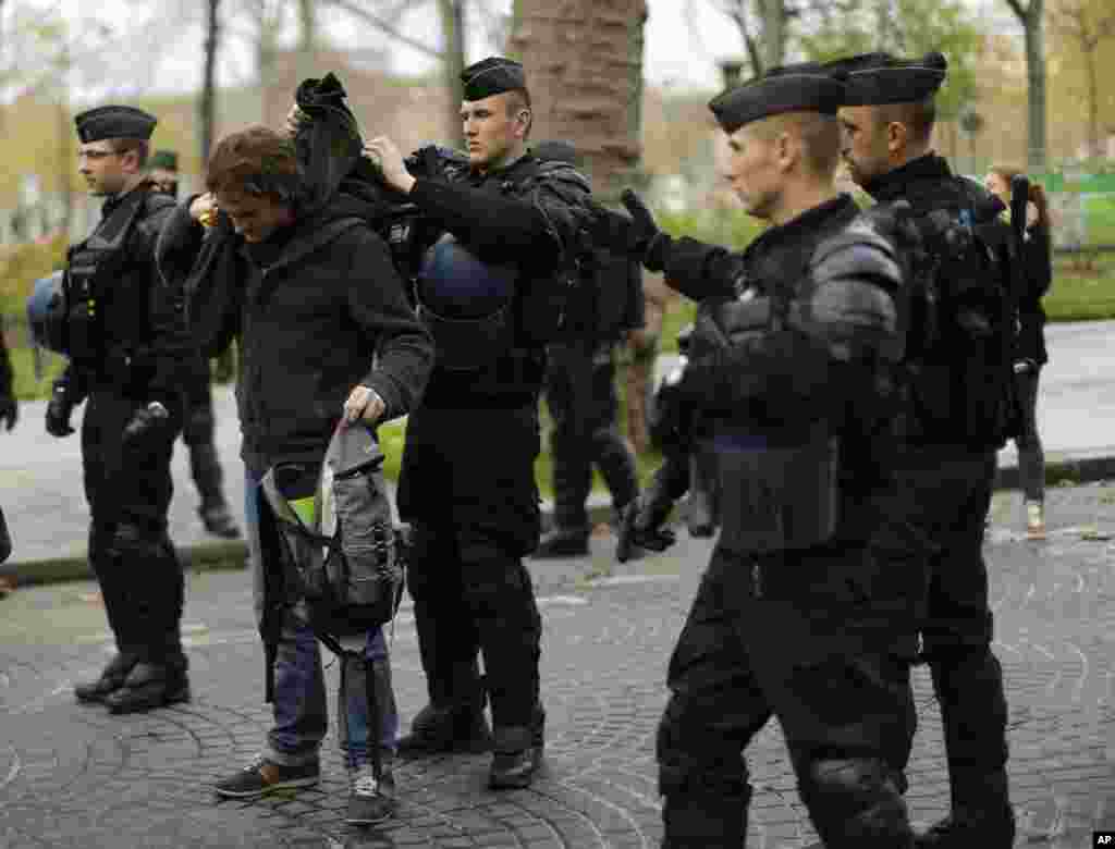 A demonstrator is searched before a protest near the Eiffel Tower.