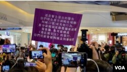 7月19日下午有区议员在元朗Yoho Mall呼吁市民关注7-21袭击事件一周年，有人高呼”光复香港、时代革命”口号，警方高举紫色旗警告违反国安法 (美国之音/汤惠芸)