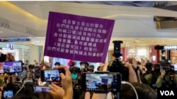 7月19日下午有區議員在元朗Yoho Mall呼籲市民關注7-21襲擊事件一週年，有人高呼”光復香港、時代革命”口號，警方高舉紫色旗警告違反國安法。(美國之音湯惠芸)