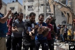اسرائیلی بمباری سے ایک عمارت کے ملبے میں دب کر ہلاک ہونے والے ایک بچے کو سوگوار فلسطینی لے جا رہے ہیں۔ فائل فوٹو